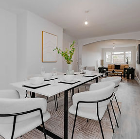 Airbnb dining area styled with white tableware, upholstered chairs and an open-plan living space
