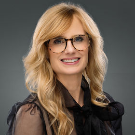 Professional business headshot of woman with glasses, studio background