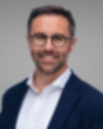 Corporate headshot of male professional wearing glasses with relaxed confident demeanor