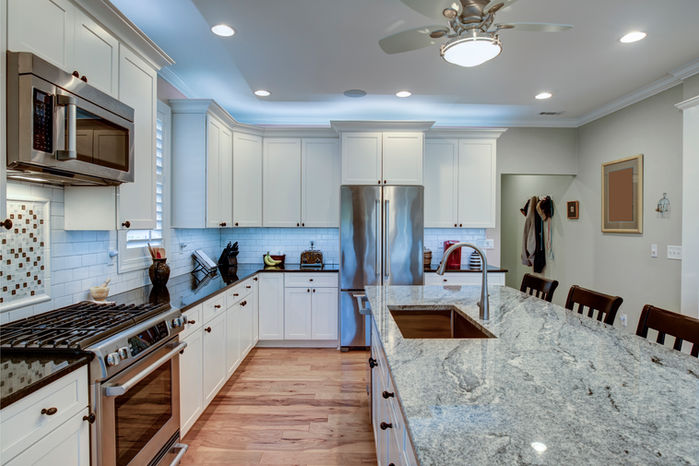 House with chic, modern, renovated kitchen with marble counters. Kitchen with large marble island with an inbuilt sink and classic white cabinets and stainless steel modern appliances. Brightly lit modern spacious kitchen in Real Estate Photography, Cairns, Queensland, Australia.