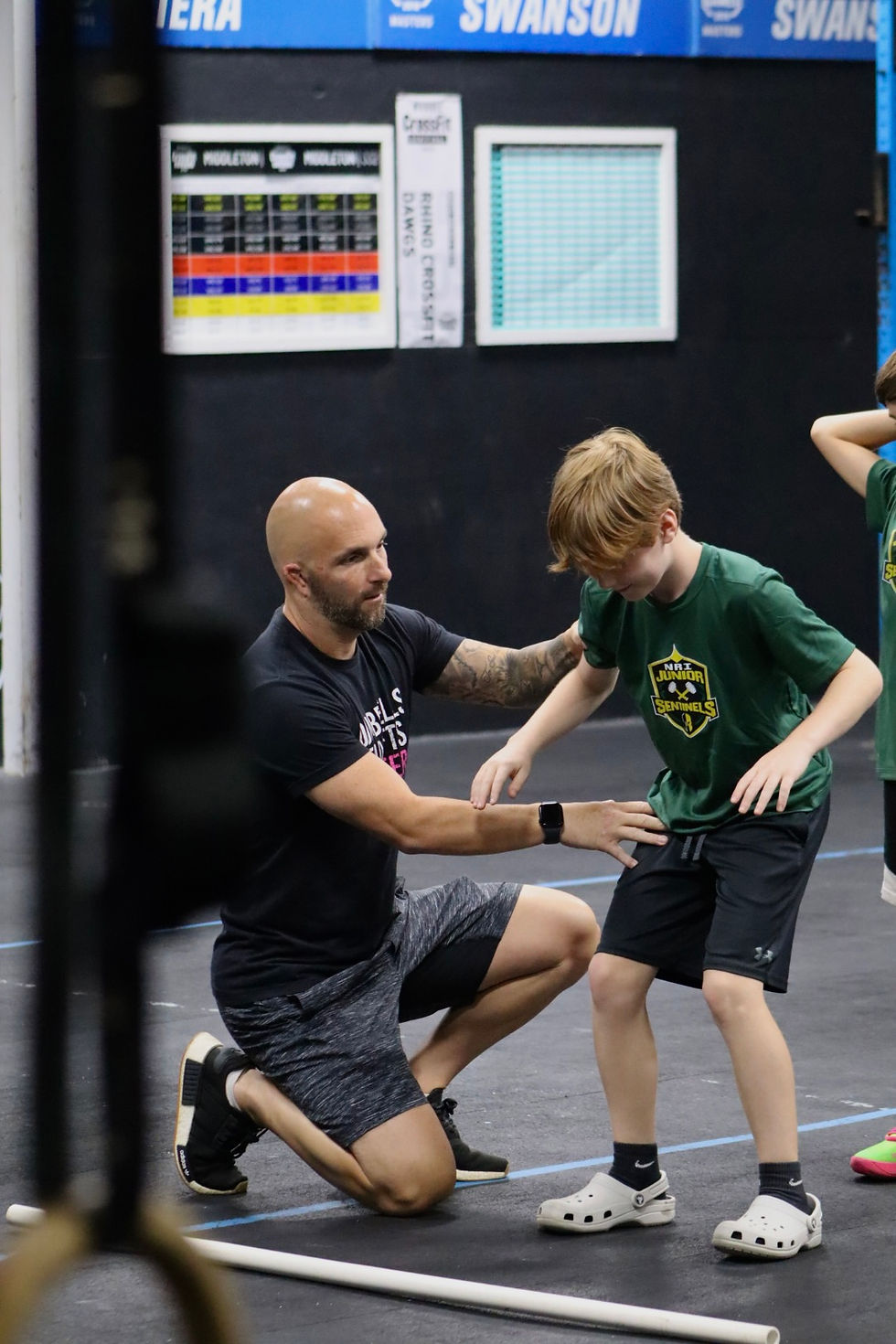 coach-instructing-young-athlete-crossfit-gym