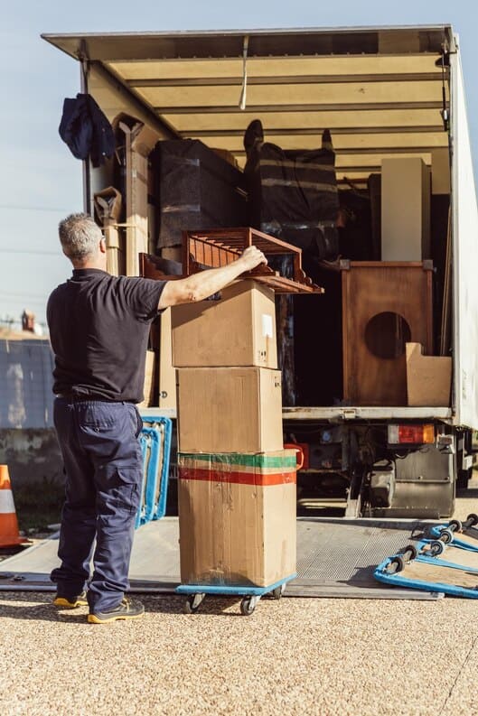 [freepicdownloader.com]-older-worker-brings-pile-cardboard-boxes-truck-moving-operation-me