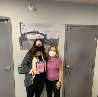 A-M Mawhiney and another person holding Mawhiney's novel, Spindrifts, at a booksigning. Both are wearing pandemic facemasks.