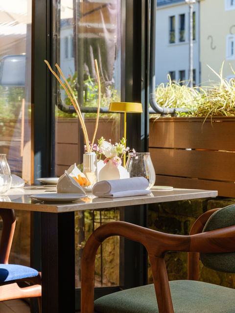 Bright restaurant table set for dining with elegant wooden chair.