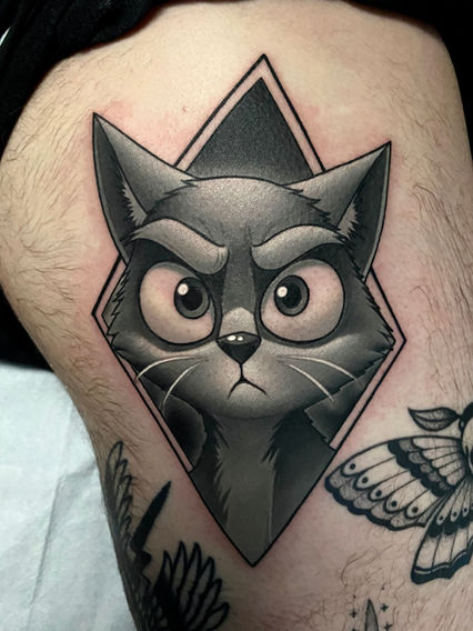 Black and grey cat portrait tattoo framed in a geometric diamond shape with detailed shading and realism.