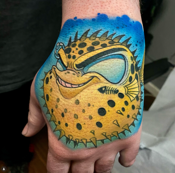 Yellow new school pufferfish tattoo on the hand in a bold illustrative style by Joe Swider in Connecticut