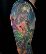 The upper arm of a full tattoo sleeve featuring a female astronaut looking up into a starry sky with a planet and a rocket in the foreground done by the best color tattoo artist in Connecticut, Cracker Joe Swider
