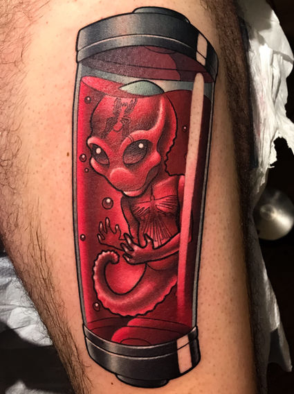 Red color thigh tattoo of an alien fetus in a tube in a surreal sci-fi horror style by Joe Swider in Connecticut
