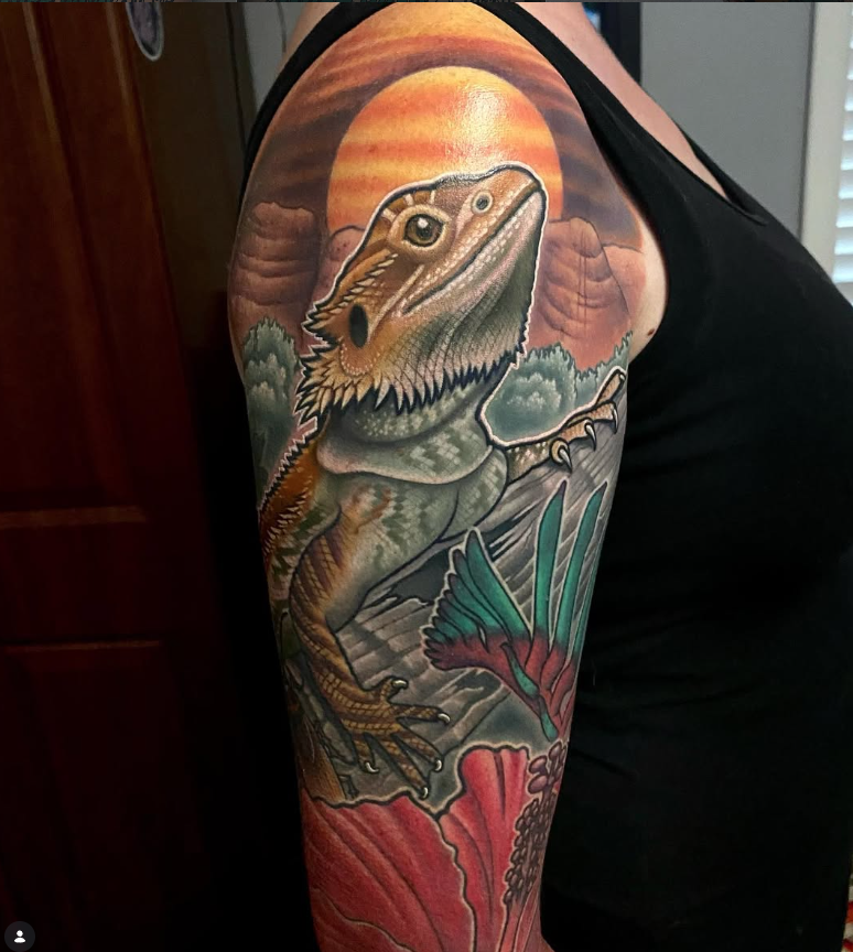 Color sleeve tattoo of a bearded dragon with flowers and a sunset background by Joe Swider in Connecticut