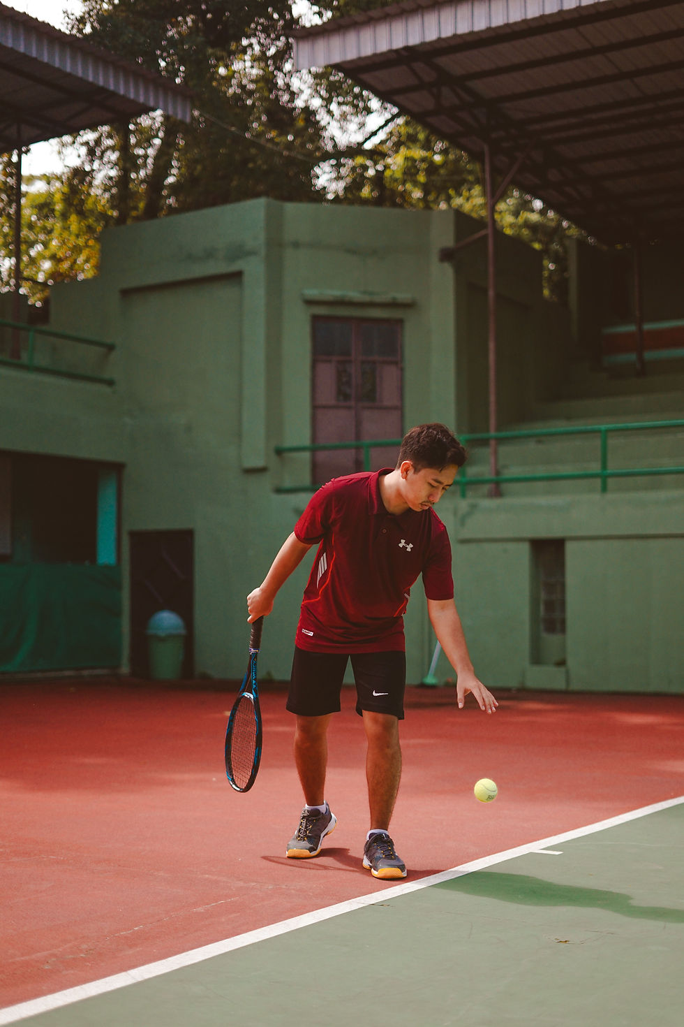 Close-up view of a hand bouncing a tennis ball beside the baseline