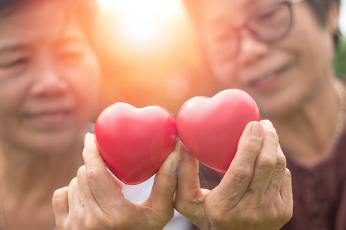Two women holding red heart shapes, symbolizing unity, connection, and becoming one heart and one mind