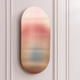 An elongated oval-shaped glass artwork mounted on a pale wall, featuring soft gradients of colour and vertical striations.