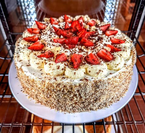 Erdbeerkuchen mit Sahne und Schokostreusel liegt auf einem Teller im Ofen.