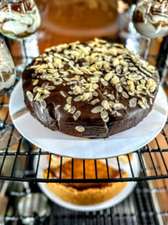 Schokoladenkuchen mit Mandelsplittern und Dessertgläsern in einer Glasvitrine.