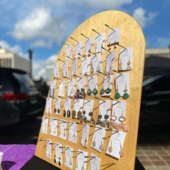 A wooden tombstone-shaped board with many different pairs of earrings on it