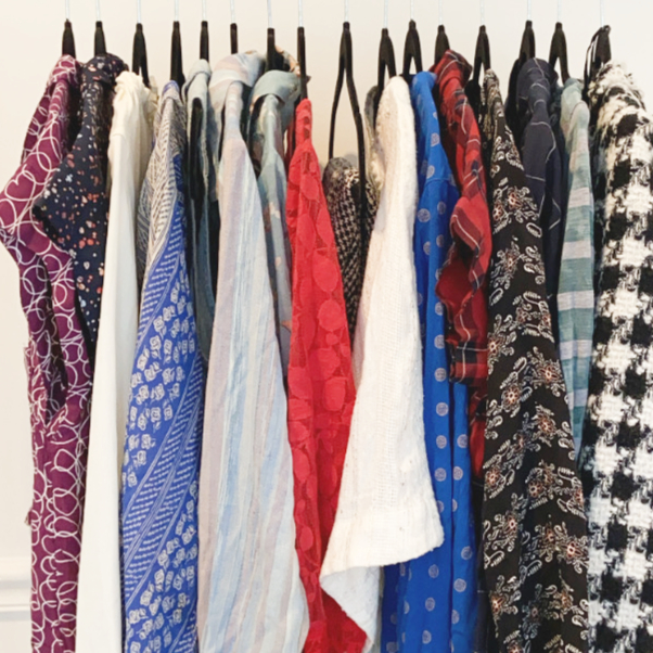 A minimalist and organized closet showing high-quality neutral-toned clothing items hanging neatly.