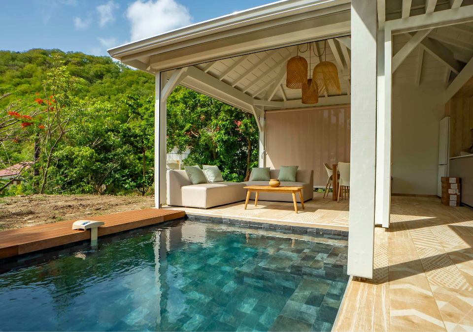 Piscine en bois de la Villa Pompierre entourée de végétation tropicale, espace détente sous terrasse couverte.
