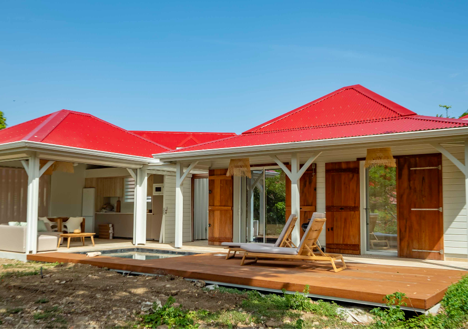 Façade de la Villa Pompierre avec architecture créole, volets en bois et toit rouge typique.