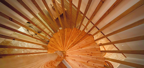 Escalier en colimaçon en bois menant à la mezzanine, vue en contre-plongée.