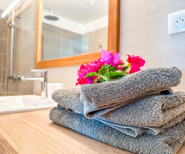 Salle de bain élégante avec des serviettes de bain grises soigneusement décorées de fleurs, offrant une ambiance de confort et de luxe.