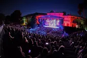 Hay festivales que programan conciertos. Y luego está Les Nits de Barcelona, esa anomalía elegante del verano barcelonés que consigue transformar los Jardines del Palacio de Pedralbes en algo mucho más cinematográfico: un oasis nocturno donde la música, la gastronomía y el cielo de julio conviven como si la ciudad hubiese decidido bajar el ritmo durante unas horas.