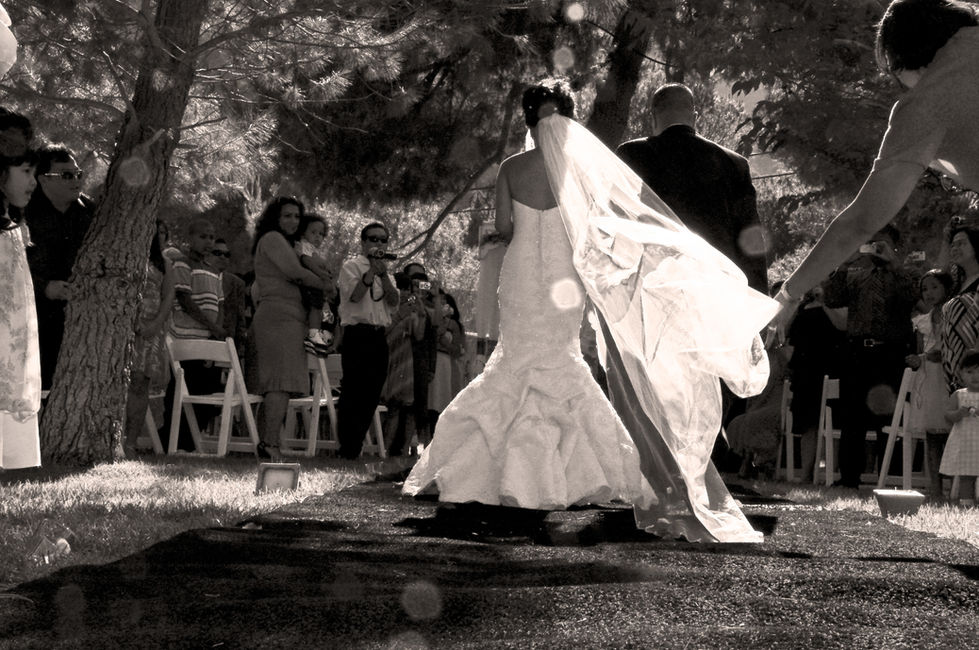 a bride is walking down the aisle with her veil blowing in the wind