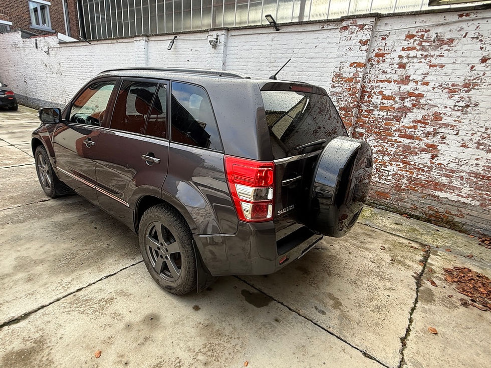 Schuin achteraanzicht van grijze Suzuki Grand Vitara met reservewiel, ingevoerd uit Moldavië en ingeschreven in België.
