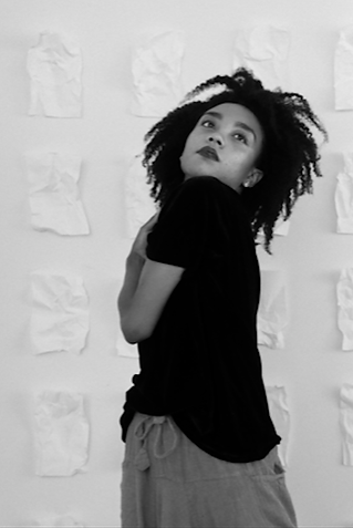 Marcella Lewis stands looking over her shoulder in black and white with a black shirt on.