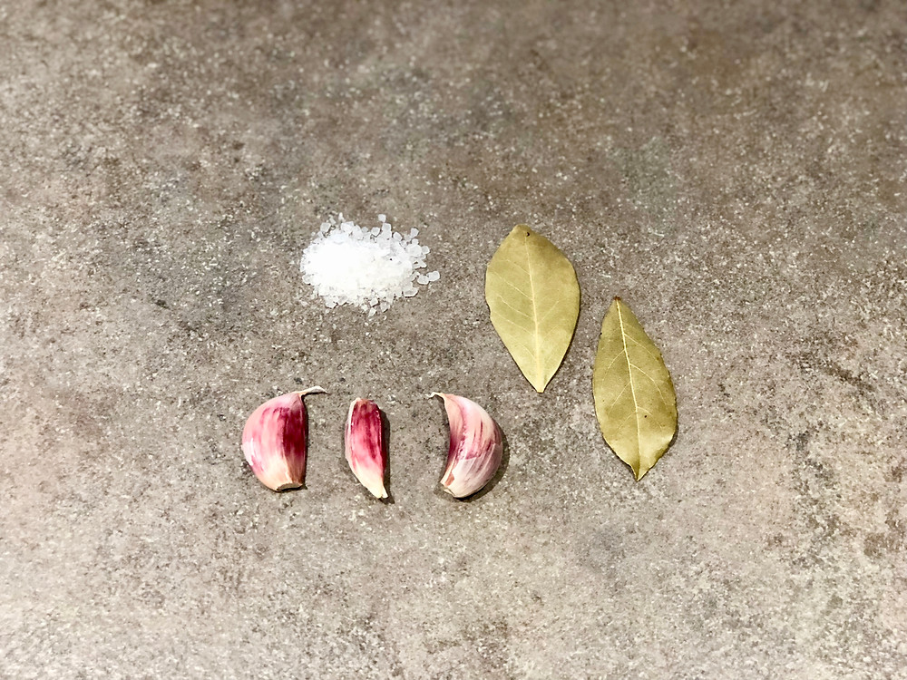 pile of rock salt, two bay leaves, three cloves of garlic