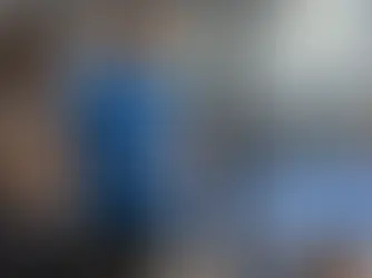 Dwie osoby rozmawiają przy szklanej ścianie kortu padlowego, w tle trwa gra.