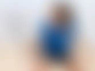 Skupiona zawodniczka squasha w niebieskiej koszulce trzyma rakietę pod kątem, przygotowując się do zagrania.