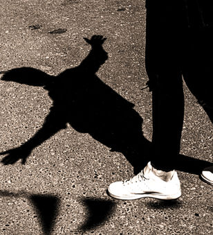 Person's legs on asphalt, their long shadow appears to be falling.