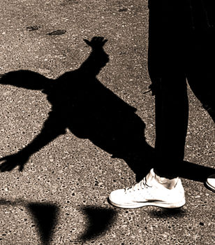 Person's legs on asphalt, their long shadow appears to be falling.