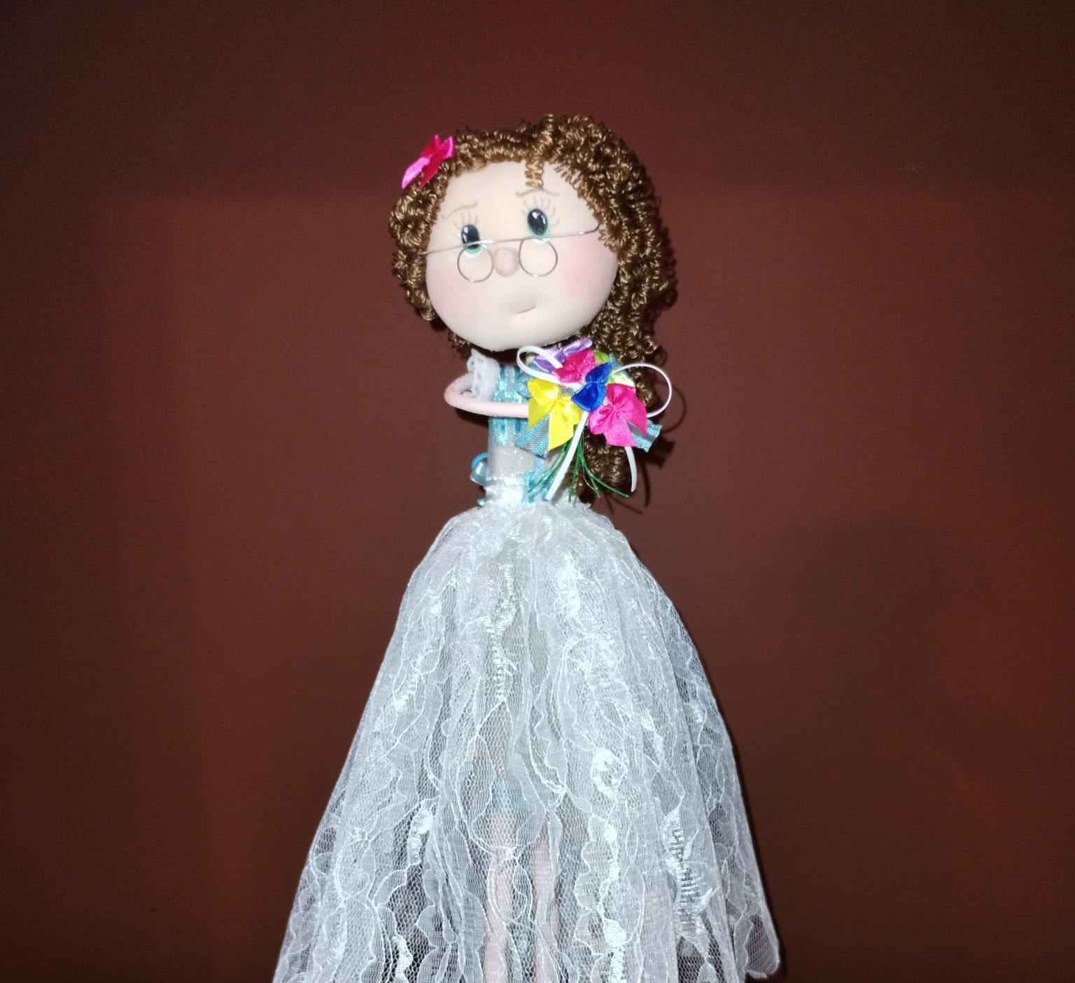 Handmade decorative doll dressed on white organza skirt and blouse carrying a bunch of delicate colorful ribbons (front)