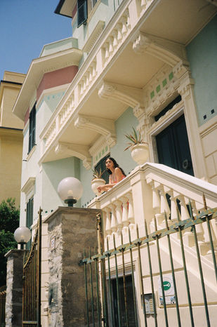 A person standing on a sunny balcony of a classic villa in Cinque Terre.