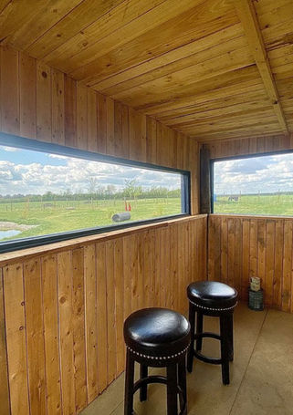 Wooden interior with two stools, long window, green field view.
