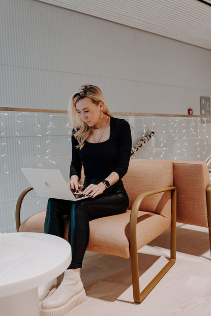 Julia C Woellner sitzt in einer Lounge und tippt in ihren Laptop