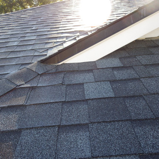 Sloped shingled roof with sun in background