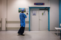 Een papa wandelt heen en weer bij de ingang van het operatiekwartier. 