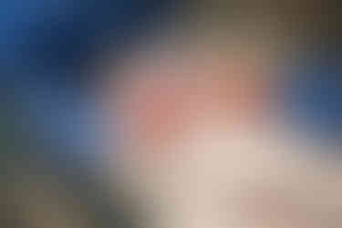 Een kinderarts luistert naar het hartje terwijl de baby een vinger van de papa vasthoudt. 