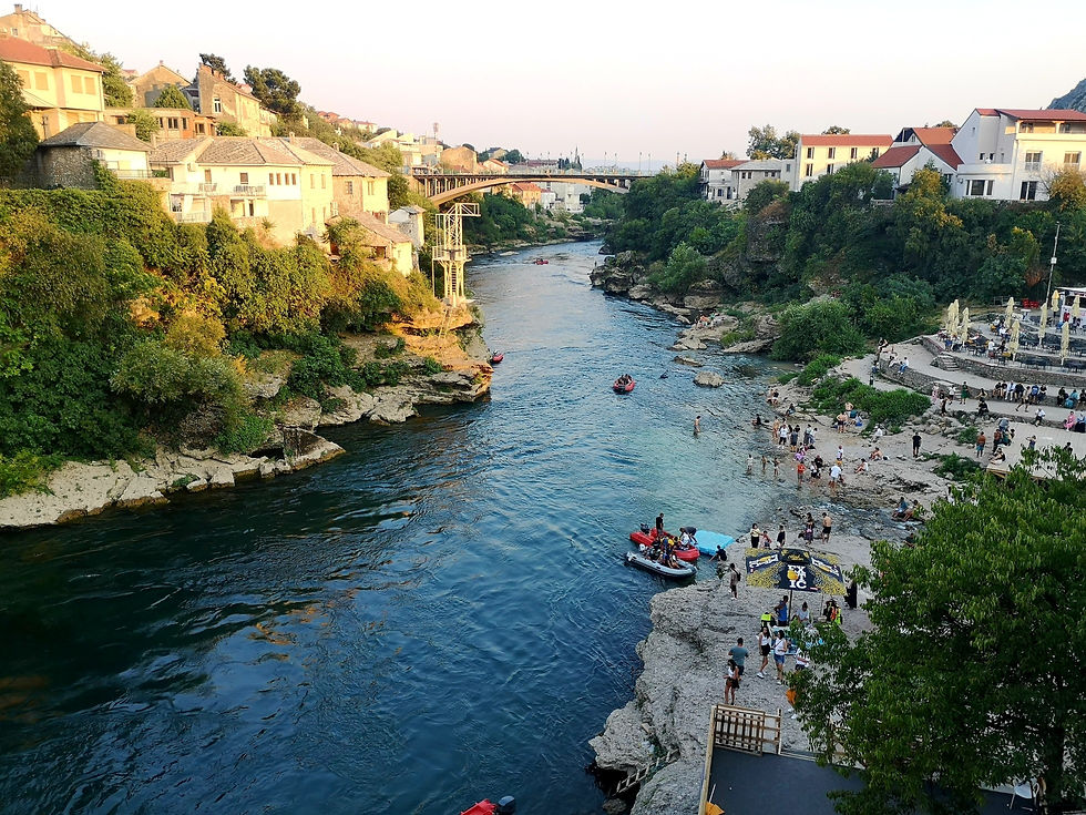 Blick von der Brücke in Mostar auf den Fluss Neretva mit Stadtstrand und Badenden.