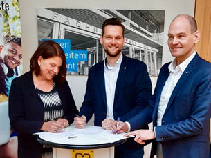 Prof. Anja Wollesen, Michael Schittek und Thomas Bultjer unterzeichnen eine Kooperationsvereinbarung in der Marktbude in Heide
