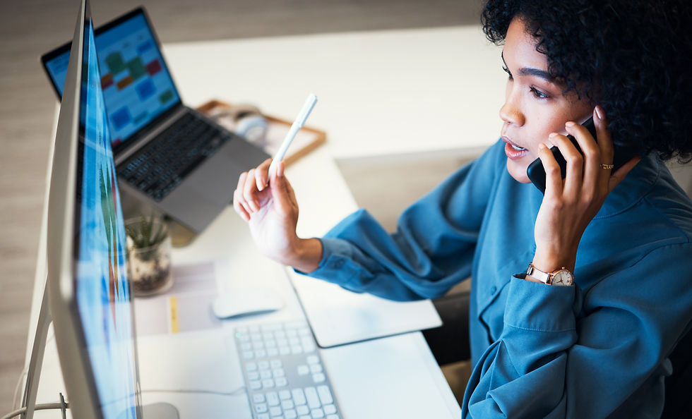 Frau arbeitet am Computer mit Diagrammen auf dem Bildschirm und telefoniert gleichzeitig