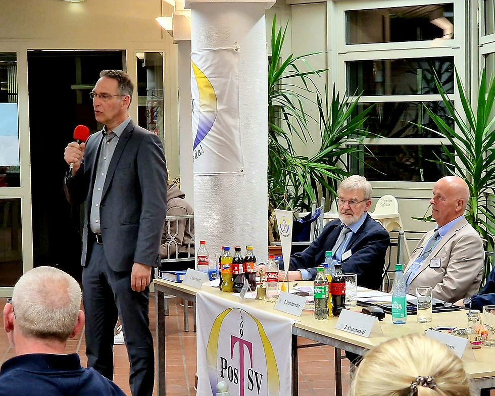 Oliver Schmidt-Gutzat spricht mit Mikrofon bei der Jahreshauptversammlung des Postsportvereins Heide