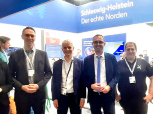 Oliver Schmidt-Gutzat mit Gruppe von Personen am Gemeinschaftsstand Schleswig-Holstein auf der Hannover Messe, darunter Dr. Hinrich Habek von der WT.SH und Minister Schrödter