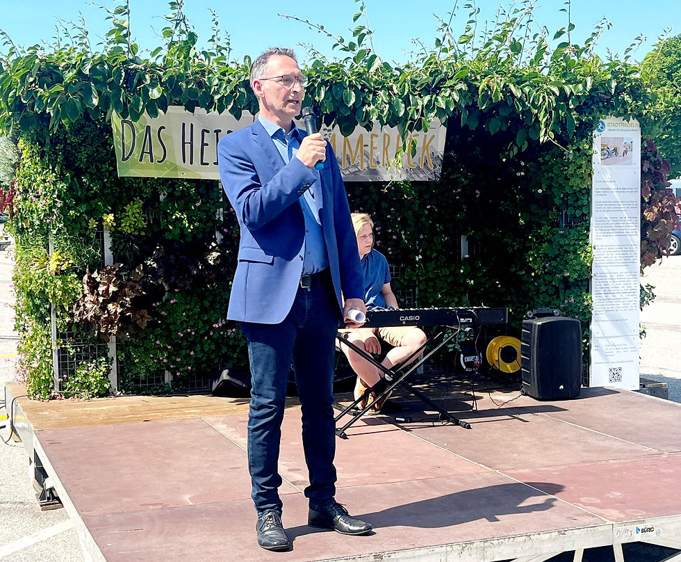 Oliver Schmidt-Gutzat spricht zur Eröffnung des Grünen Zimmers in Heide. Im Hintergrund ist die begrünte Bühne mit Schriftzug „Das Heider Sommereck“ zu sehen.