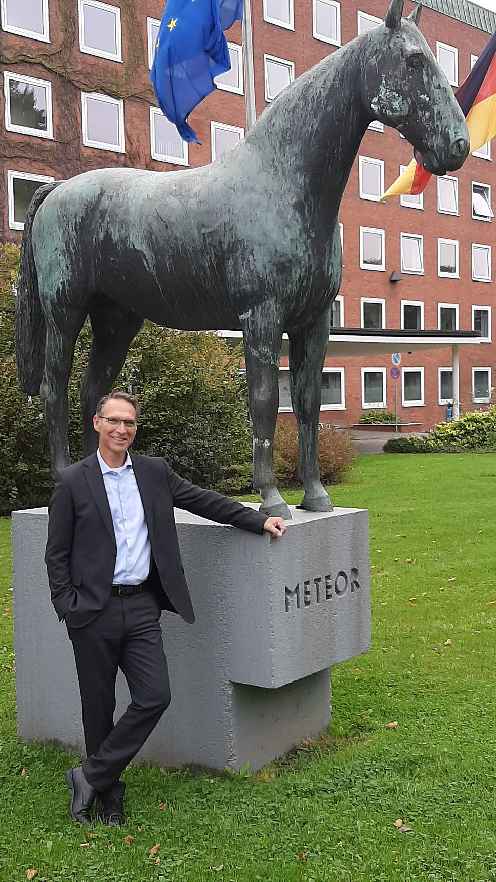 Oliver Schmidt-Gutzat vor der Staatskanzlei Kiel mit Blick auf das Gebäude und die Landesflaggen