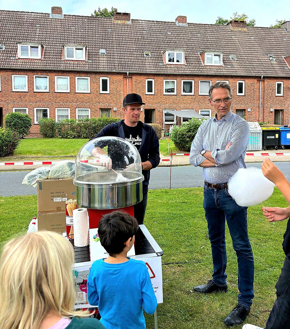 Michael Schrader vom Jugendzentrum macht Zuckerwatte beim Kinderfest in Heide, Oliver Schmidt-Gutzat schaut zu.