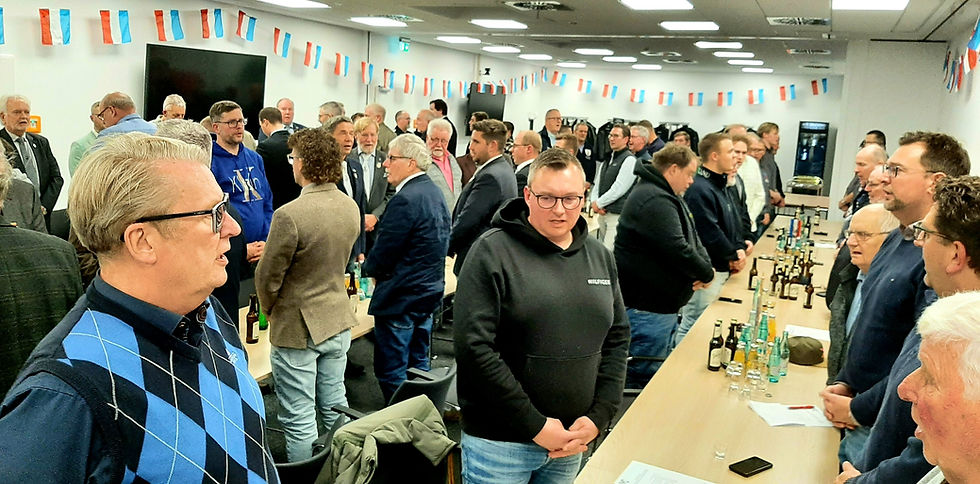 Teilnehmende der Dree-Eggen-Versammlung stehen im dekorierten Raum zur Vorbereitung auf das Hohnbeerfest.