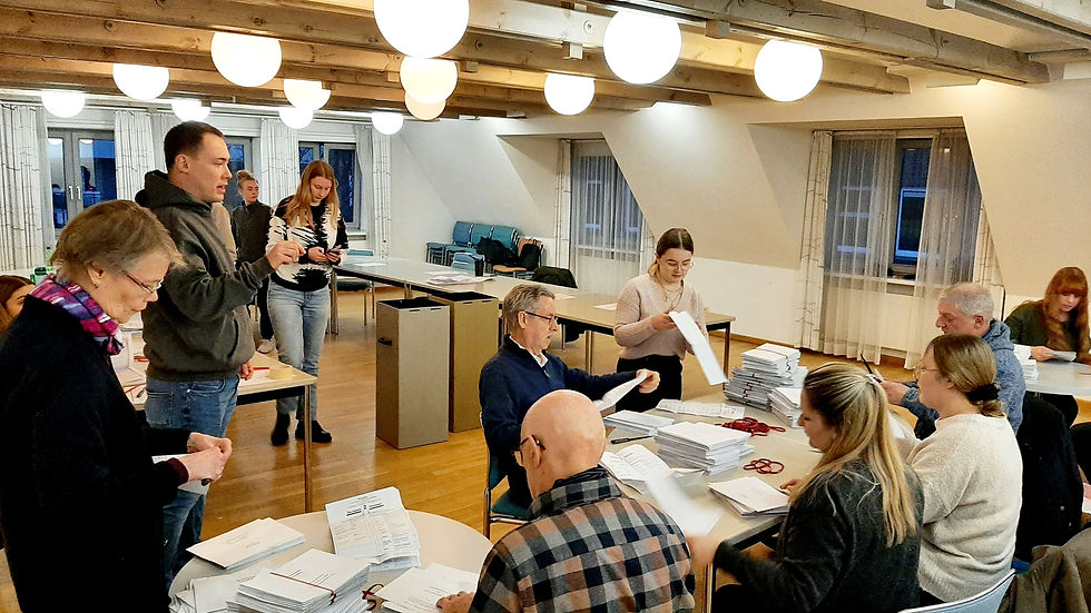 Wahlhelfer bei der Stimmauszählung im Briefwahllokal 2 im Bürgerhaus Heide, Menschen sitzen an Tischen mit Wahlunterlagen.